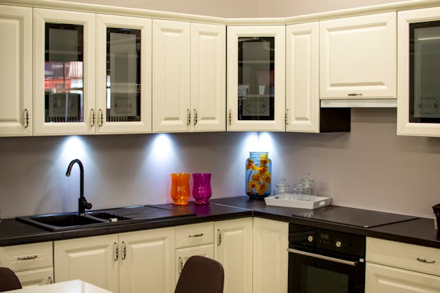 A Kitchen with black coountertops and white cupboards